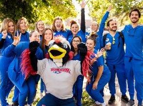 A group of nursing students in blue scrubs celebrating on 9th Street Mall with Rowdy the Roadrunner in the center